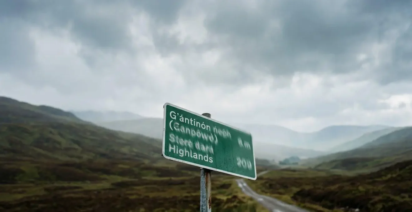 Bilingual Scottish road sign in misty Highland landscape with mountains in background